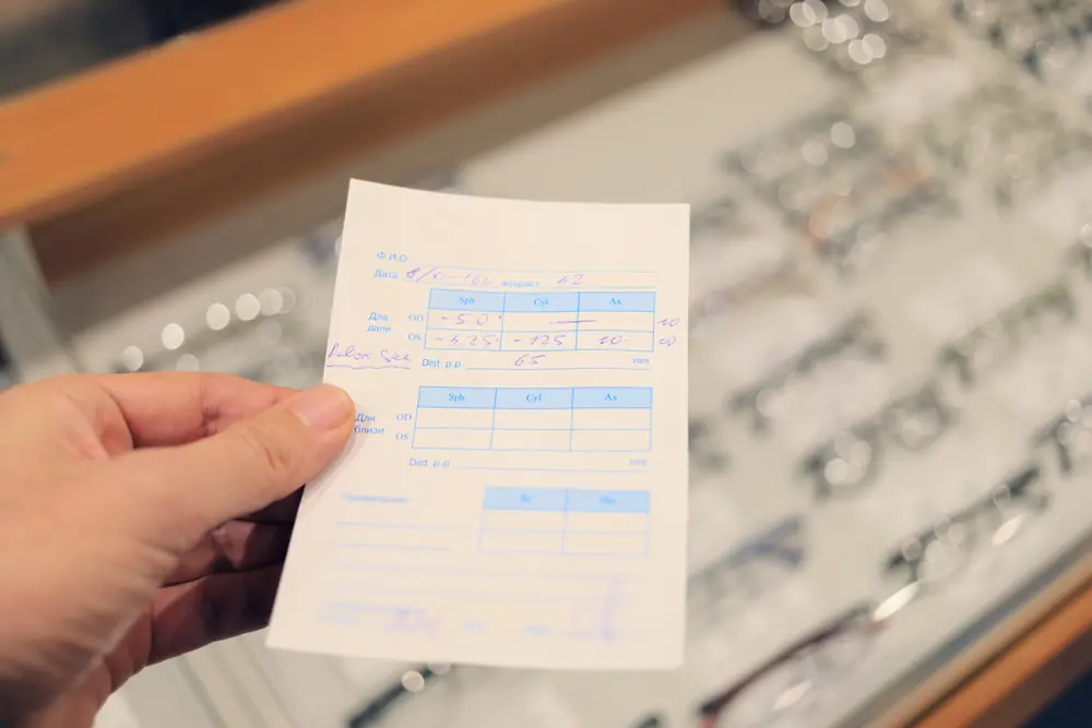 Someone reading an eye prescription chart near a display case of eye glasses.